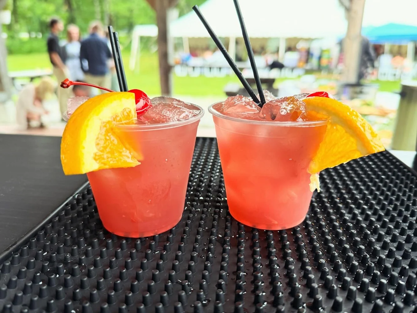 Two signature cocktails garnished with orange and cherry